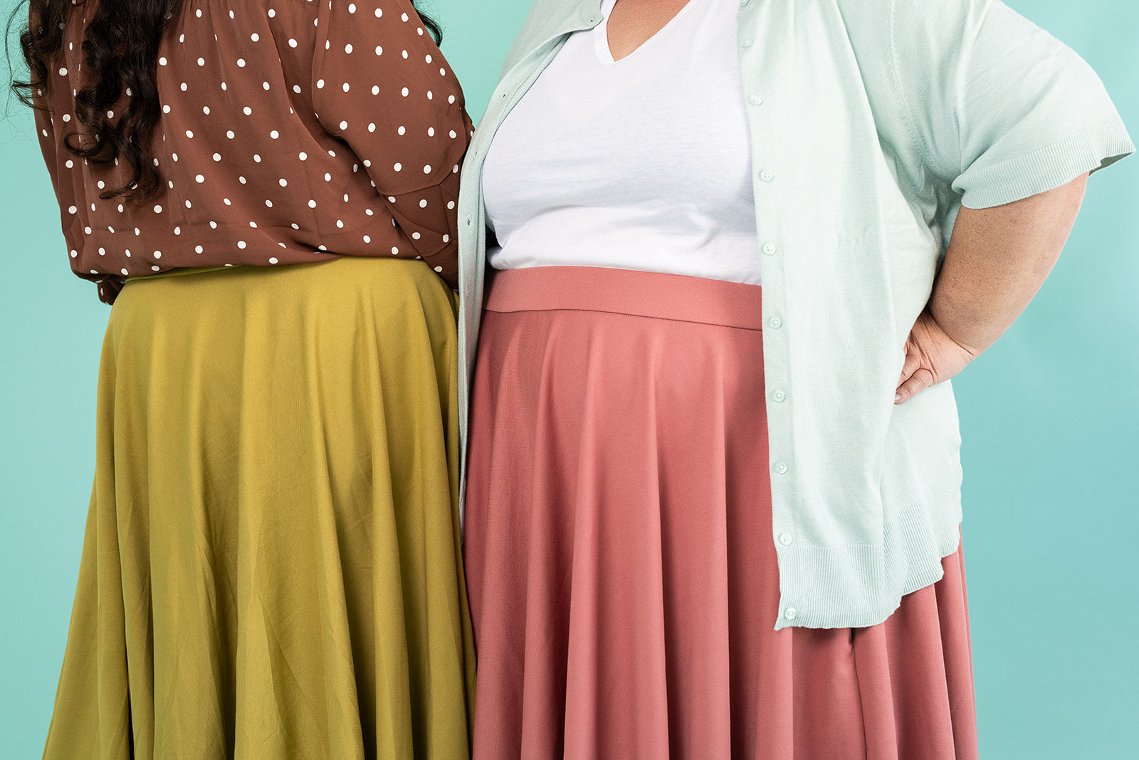 Two people are shown modelling skirts. One is wearing a brown shirt with polka dots and a mustard coloured skirt. The second woman is wearing a white tshirt, light blue cardigan and a pink skirt